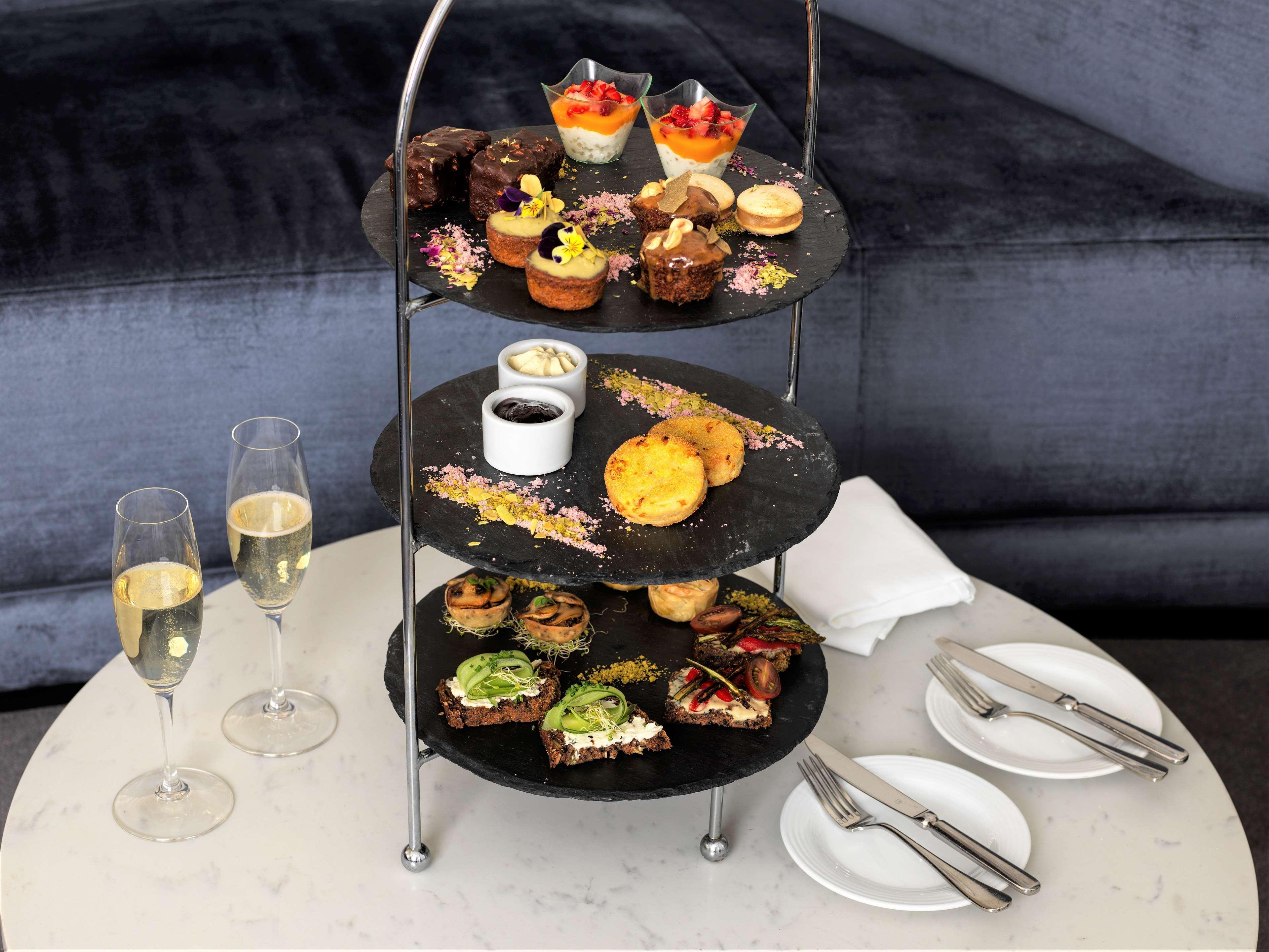 Radisson Blu Plaza Hotel Sydney Eksteriør billede The photo depicts a tiered serving stand filled with various desserts and snacks. The stand has three levels:

1. **Top Tier**: Features a selection of small desserts, including colorful cups of fruit, cakes, and pastries.
   
2. **Middle Tier**: Con
