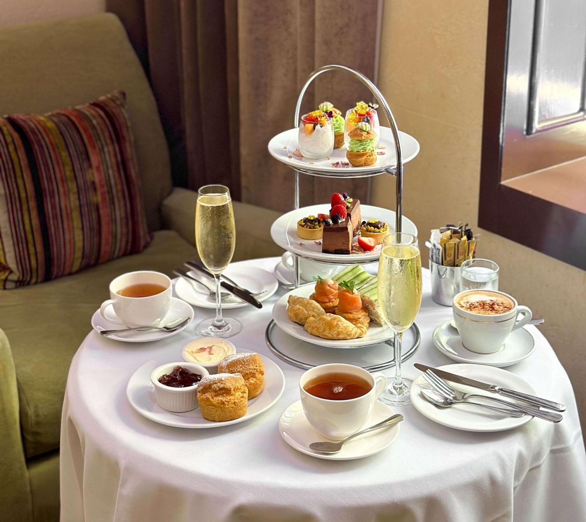 Radisson Blu Plaza Hotel Sydney Eksteriør billede The photo depicts a beautifully arranged table set for afternoon tea. At the center, there is a three-tiered stand filled with a variety of desserts, including small cakes, pastries, and fruit-topped treats. Surrounding the stand are cups of tea and 