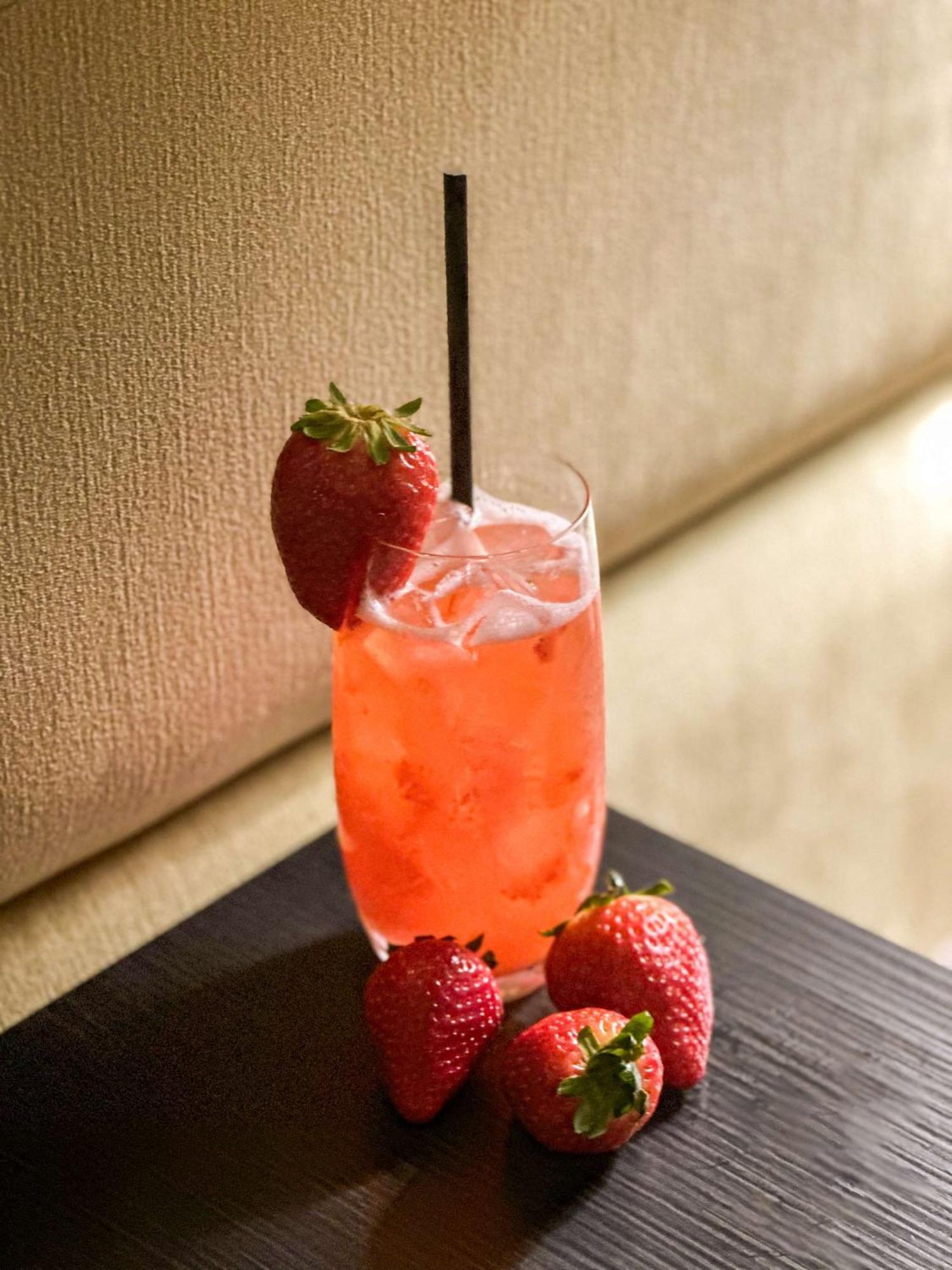 Radisson Blu Plaza Hotel Sydney Eksteriør billede The photo shows a refreshing beverage in a tall glass. The drink is a vibrant pink color and appears to be served over ice. It has a black straw inserted into it. Adorning the glass are fresh strawberries on the rim, complementing the drink. Addition